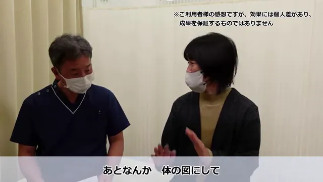 長年の肩こりと繰り返すめまいが根本改善したKさんの声 丁寧な問診・カウンセリングの様子。クリーム色のカーテンがかかった部屋で、マスクをかぶった2人が座って話している。画像の上下に日本語の文字が見える。右側の人物は話しながら手でジェスチャーをしている。
